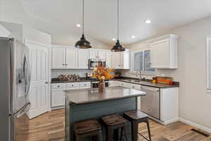 Kitchen with a center island, sink, light wood-type flooring, appliances with stainless steel finishes, and white cabinetry