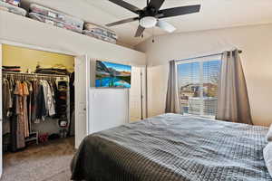 Bedroom with ceiling fan, vaulted ceiling, a walk in closet, a closet, and carpet