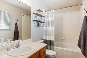 Full bathroom featuring vanity, toilet, and shower / bathtub combination with curtain