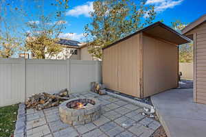 View of patio featuring a shed and an outdoor fire pit