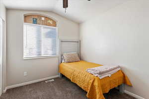 Carpeted bedroom featuring ceiling fan and lofted ceiling