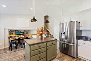 Kitchen featuring white cabinets, green cabinets, stainless steel fridge with ice dispenser, and light hardwood / wood-style floors