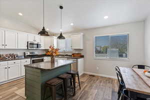 Kitchen with white cabinets, light wood-type flooring, stainless steel appliances, and a wealth of natural light