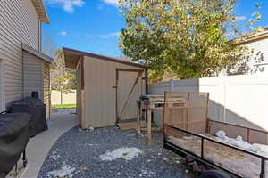 View of patio featuring a storage shed and a grill