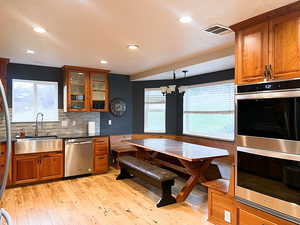 Kitchen featuring sink,  hardwoode flooring, appliances with stainless steel finishes, decorative light fixtures, and a chandelier