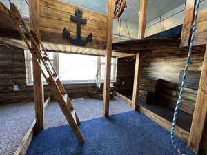 Unfurnished bedroom featuring carpet flooring and wooden walls