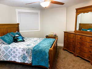 Carpeted bedroom featuring ceiling fan and a textured ceiling