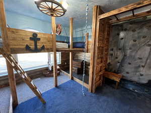 Bedroom featuring wood walls, carpet floors, and a textured ceiling