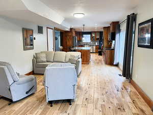 Living room featuring hardwood floors large windows, and the kitchen in the background