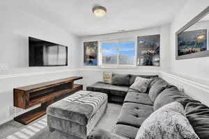 Lower level family room featuring light colored carpet and a textured ceiling