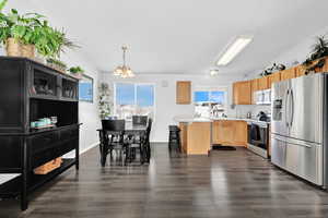 Kitchen featuring sink, appliances with stainless steel finishes, decorative light fixtures, dark hardwood / wood-style flooring, and a chandelier