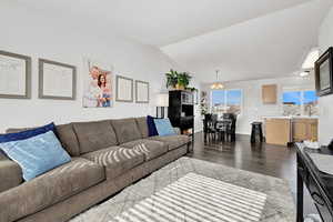 Great room featuring dark wood-type flooring, lofted ceiling, and an inviting lighting