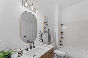 Full bathroom with vanity, tiled shower / bath combo, and toilet