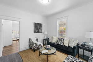 Living room with wood-type flooring and ornamental molding