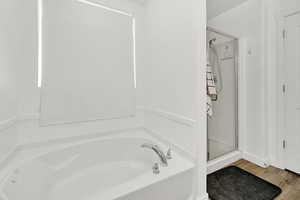 Bathroom with hardwood / wood-style flooring and separate shower and tub