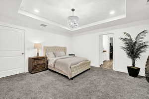 Bedroom featuring a raised ceiling, carpet flooring, and a chandelier