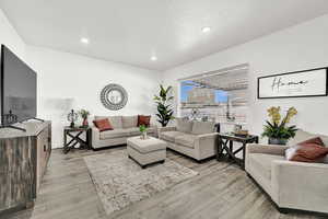 Living room with a textured ceiling and light hardwood / wood-style flooring