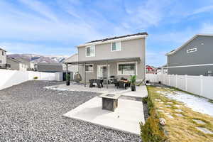 Back of property with a mountain view, an outdoor living space with a fire pit, and a patio