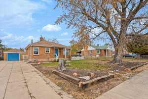 View of front of home with a garage, an outdoor structure, and a front lawn