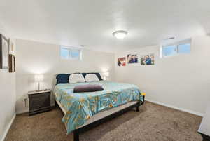 Bedroom with dark carpet and a textured ceiling