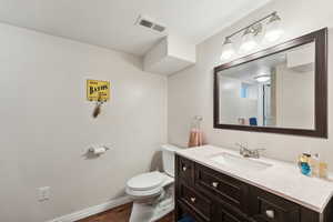 Bathroom featuring vanity, hardwood / wood-style flooring, and toilet