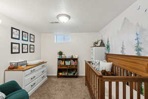 Carpeted bedroom with a crib and a textured ceiling