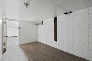 Unfurnished room featuring wood-type flooring and brick wall