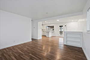 Unfurnished living room with dark wood-type flooring