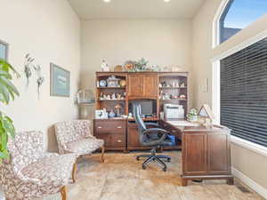 Home office featuring light tile patterned floors and a towering ceiling