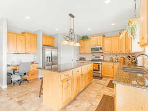 Kitchen featuring light stone counters, sink, a center island, and stainless steel appliances