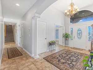 Entryway featuring ornate columns, light tile patterned floors, and an inviting chandelier