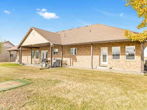 Rear view of property with a lawn and a patio area