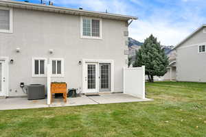 Rear view of house featuring a lawn, central air condition unit, and a patio