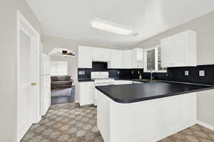 Kitchen with white cabinetry, sink, ceiling fan, kitchen peninsula, and white appliances