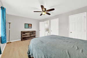 Bedroom with light wood-type flooring, ensuite bathroom, and ceiling fan