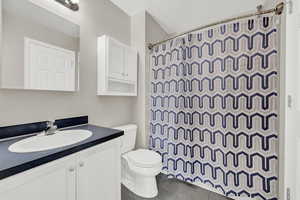 Bathroom with tile patterned floors, vanity, toilet, and a shower with shower curtain