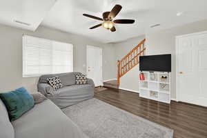 Living room featuring a textured ceiling, ceiling fan, and dark wood-type flooring