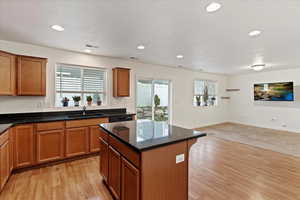 Kitchen featuring a kitchen island, light colored carpet, sink, and a wealth of natural light