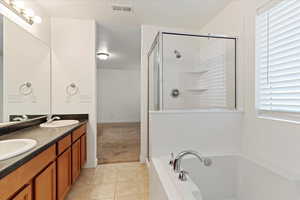 Bathroom featuring tile patterned flooring, vanity, and separate shower and tub