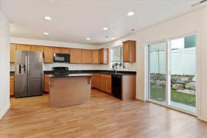 Kitchen featuring sink, a center island, black appliances, and light hardwood / wood-style floors