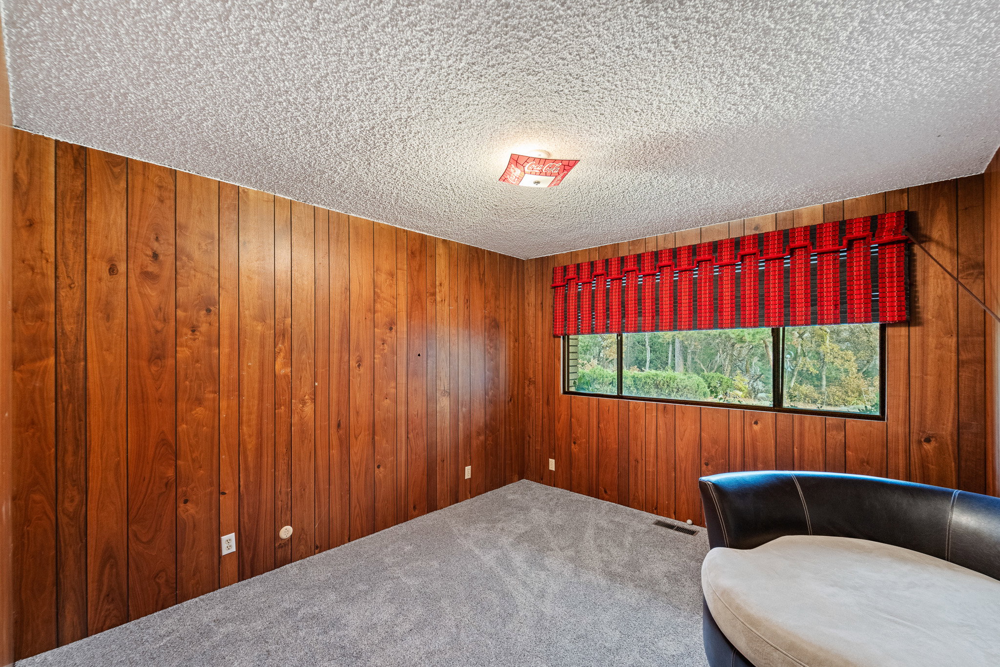 Unfurnished room featuring carpet flooring, a textured ceiling, and wood walls