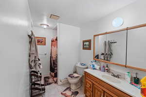 Bathroom featuring tile patterned floors, vanity, toilet, and a shower with curtain