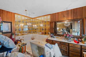 Bathroom with vanity, a textured ceiling, a chandelier, and wooden walls