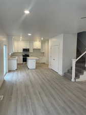 Kitchen featuring appliances with stainless steel finishes, sink, a center island, light hardwood / wood-style floors, and white cabinetry