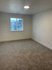 Empty room featuring carpet and a textured ceiling