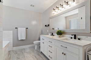 Bathroom featuring vanity, a tub to relax in, and toilet