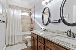 Full bathroom featuring tile patterned flooring, shower / bath combination with curtain, vanity, and toilet