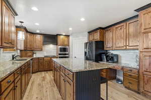 Kitchen featuring tasteful backsplash, a center island, stainless steel appliances, and light wood-type flooring