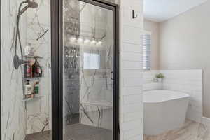 Bathroom featuring shower with separate bathtub and tile walls