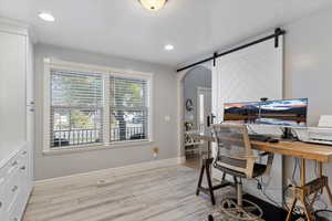 Office area featuring a barn door and light hardwood / wood-style flooring